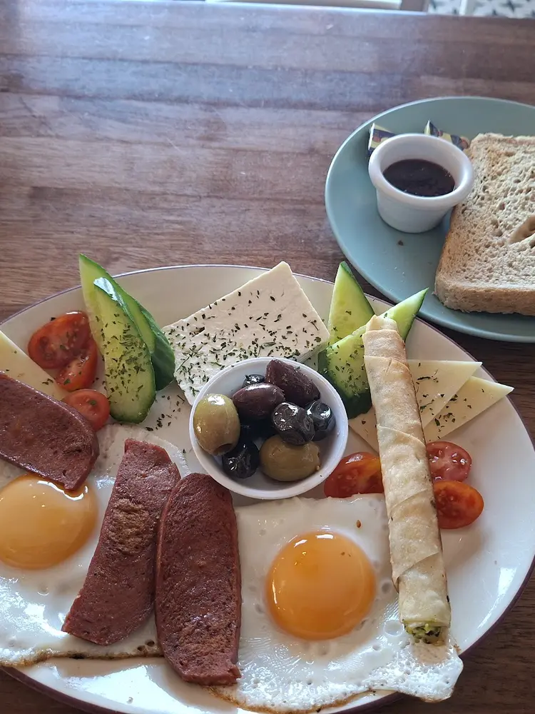 Turkish breakfast plate with sucuk, fried eggs, olives, feta and sigara böreği