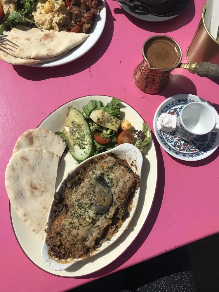 Lamb moussaka in an oven dish with salad, flatbread and Turkish coffee in a copper pot