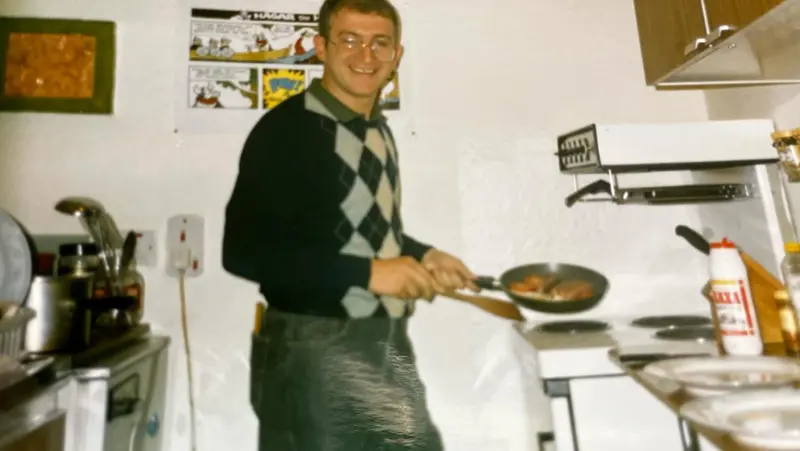 1990s photograph of a young man cooking at a home stove